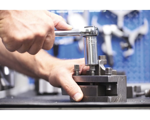 Eine Person benutzt einen Steckschlüssel, um eine Werkstückhalterung festzuziehen.