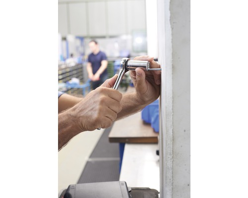 Eine Person befestigt mit einer Ratsche eine Schraube.