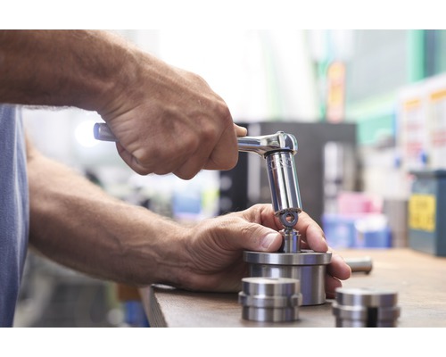 Ein Mann benutzt einen Ratschenschlüssel, um ein Metallteil zu befestigen