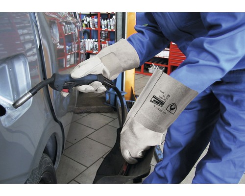 Eine Person schweißt mit Schweißhandschuhen ein Auto.