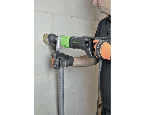 Mann bohrt mit einer Mauerdurchbruchsäge ein Loch in eine Wand.