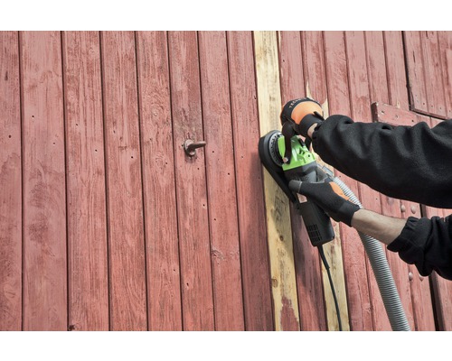 Une personne ponce une porte en bois avec une ponceuse murale.