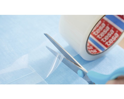 Eine Rolle Tesa Film wird mit einer Schere zugeschnitten.