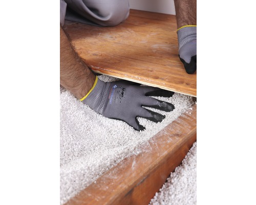 Un artisan pose un plancher en bois sur un lit de granulés isolants.