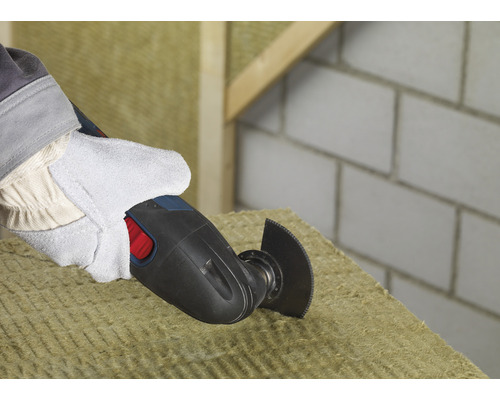 Une personne coupe un matériau isolant avec un outil multifonction.