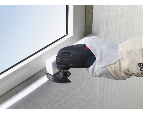 Outil électrique oscillant utilisé pour couper des panneaux isolants sur un cadre de fenêtre