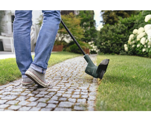 Personne utilisant un coupe-bordure dans le jardin