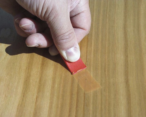 Hand entfernt Klebeband von Holz