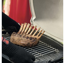 Lammkarree auf einem Grill mit Händen mit Grillhandschuhen