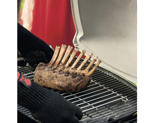 Lammkarree auf einem Grill mit Händen mit Grillhandschuhen
