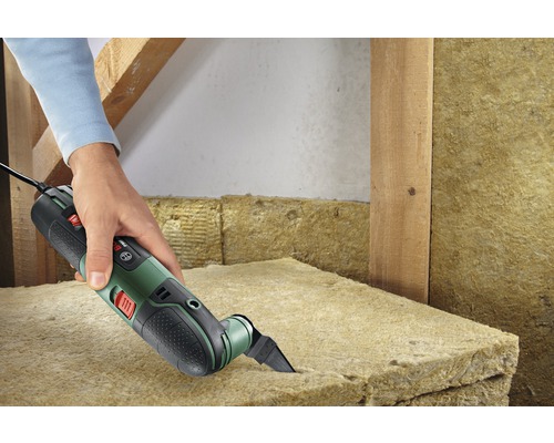 Une personne coupe de la laine isolante avec un outil multifonction.