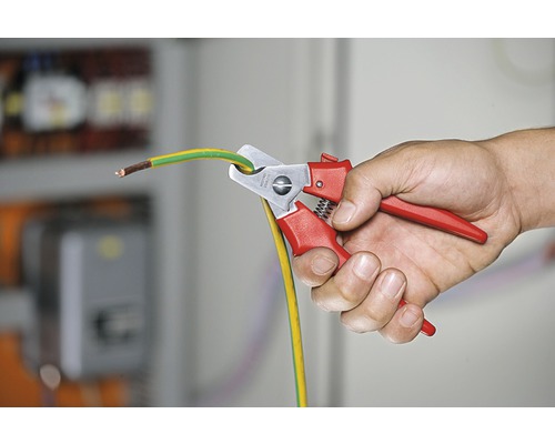 Eine Person schneidet ein Erdkabel mit einer Kabelschere