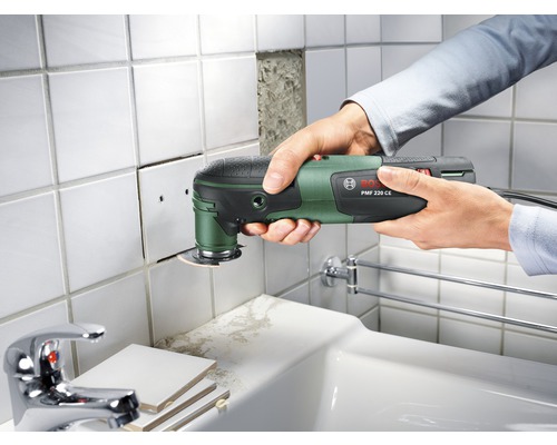 Une personne utilise un outil multifonction Bosch pour couper des carreaux.