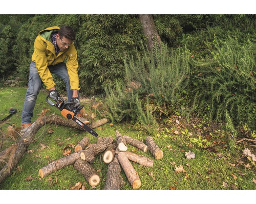 Mann sägt Holz mit einer Kettensäge im Garten.