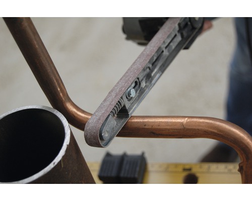 Bandschleifer beim Schleifen eines Rohres