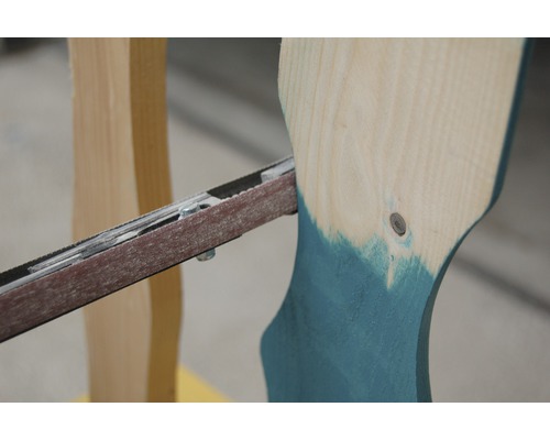 Nahaufnahme einer Bandschleifmaschine beim Schleifen eines Holzstücks