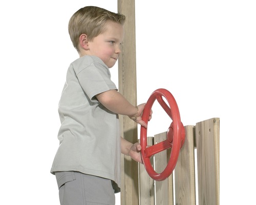 Kind spielt mit einem roten Steuerrad an einem Spielturm