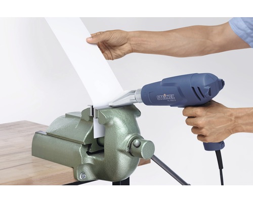 Eine Person biegt Kunststoff mit einer Heißluftpistole und einem Schraubstock.