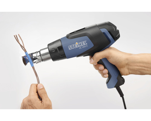 Eine Hand hält eine Heißluftpistole und erhitzt ein Kabel.