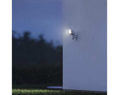 Aussenwandleuchte mit Bewegungsmelder beleuchtet eine Hauswand bei Nacht.