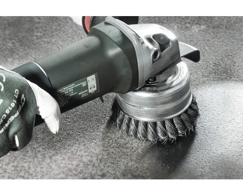 Brosse métallique montée sur une meuleuse en cours d''utilisation