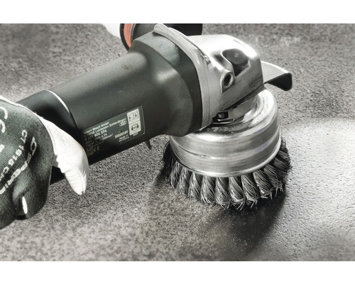 Brosse métallique montée sur une meuleuse d''angle sur une surface