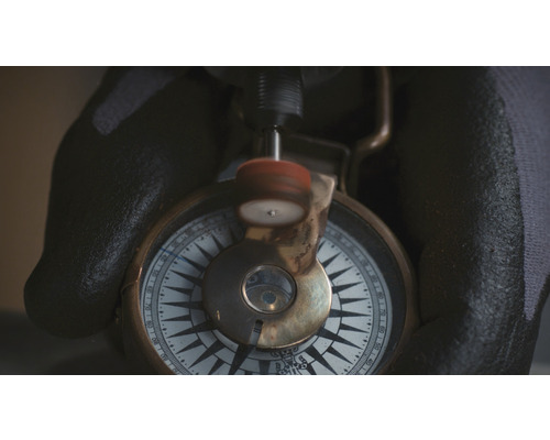 Eine Hand in einem Handschuh poliert einen Kompass.