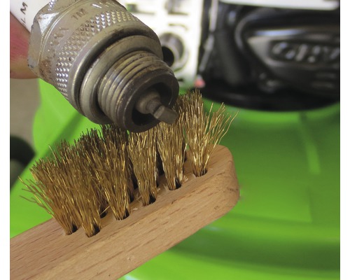 Bougie d''allumage nettoyée avec une brosse métallique.