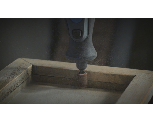 Un outil de ponçage Dremel est utilisé sur un cadre en bois.