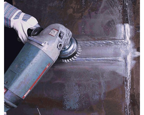 Une personne utilise une machine à brosse métallique pour nettoyer le métal.