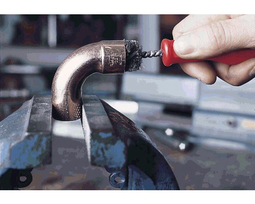 Rohrbürste reinigt ein Kupferrohr in einem Schraubstock