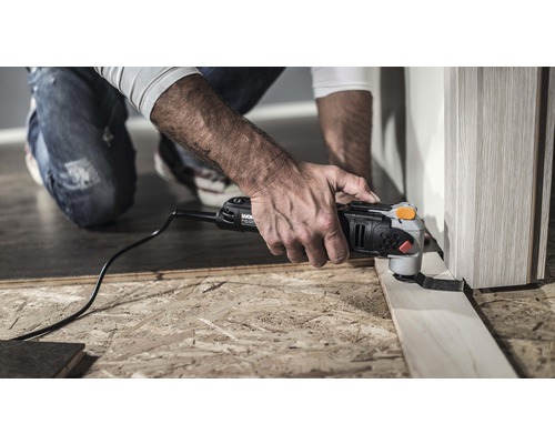 Mann verwendet Multifunktionswerkzeug zum Schneiden eines Holzstücks