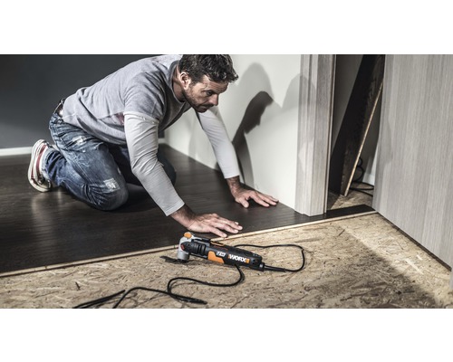 Ein Mann arbeitet mit einem Multifunktionswerkzeug von Worx an einem Bodenbelag.