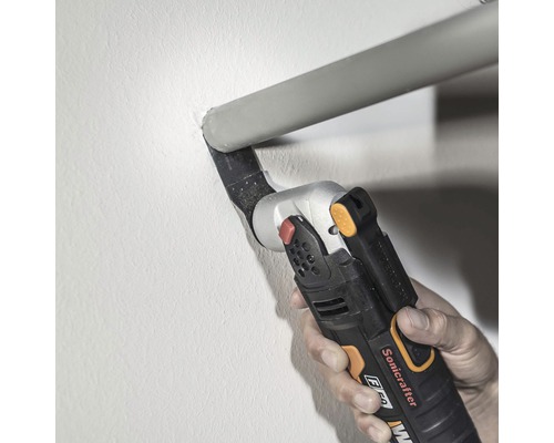 Eine Hand bedient einen Multifunktionsschneider zum Schneiden eines Rohres an einer Wand.