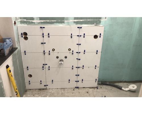 Wandfliesen in einem Badezimmer mit Fliesenzubehör und Wasserwaage.