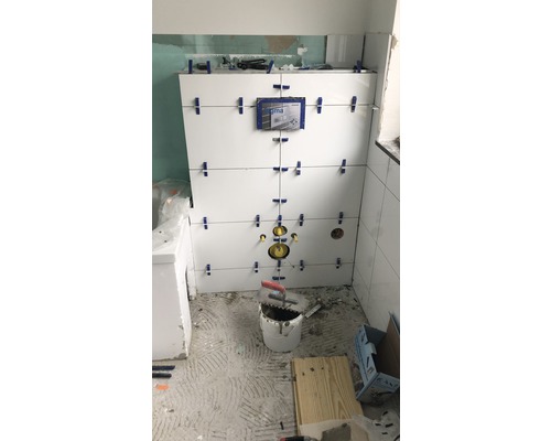 Badezimmerrenovierung mit weißen Fliesen an der Wand und Werkzeugen