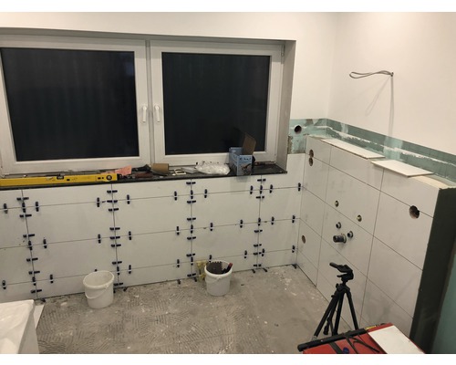 Badezimmer im Bau mit Fliesen an den Wänden, Fenster und Werkzeugen
