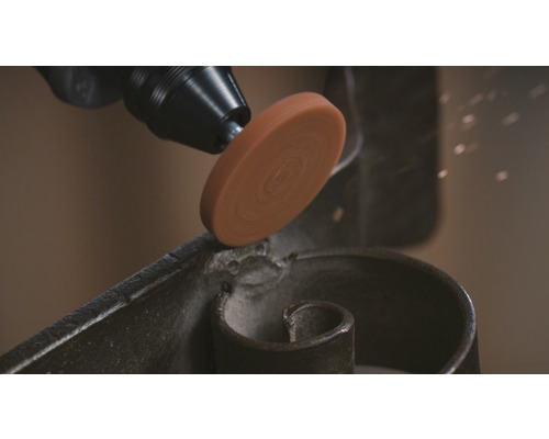 Ein Schleifwerkzeug an einem Werkstück aus Metall.