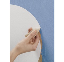 Une main retire du papier peint d''un mur.