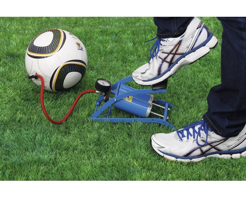 Eine Person pumpt mit einer Fußluftpumpe einen Fußball auf Rasen auf.