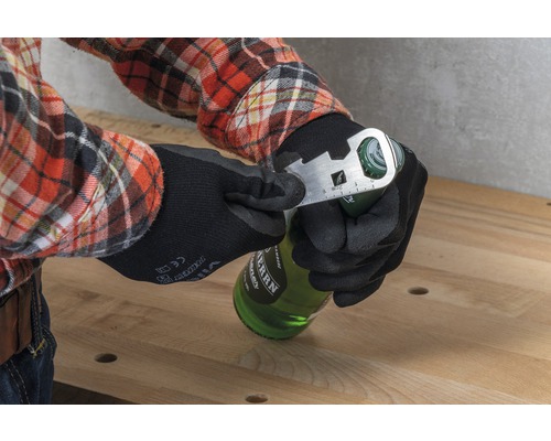 Une personne portant des gants de travail ouvre une bouteille avec un outil multifonction.