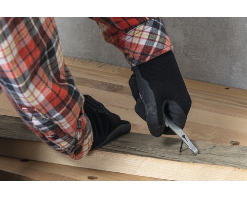 Une personne retire un clou d''une planche de bois avec un tire-clou