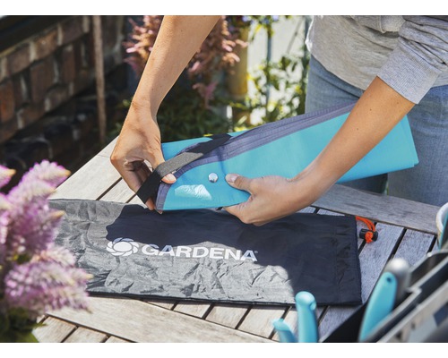 Une personne emballe un coussin de banc à genoux pour outils de jardin Gardena dans un sac.