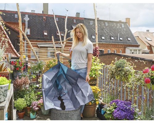 Femme versant de la terre dans un pot avec un sac de plantation sur un balcon