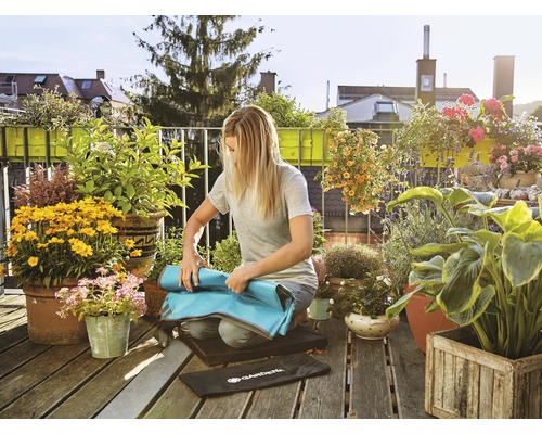 Femme enroulant un tapis de jardinage sur un balcon avec des plantes