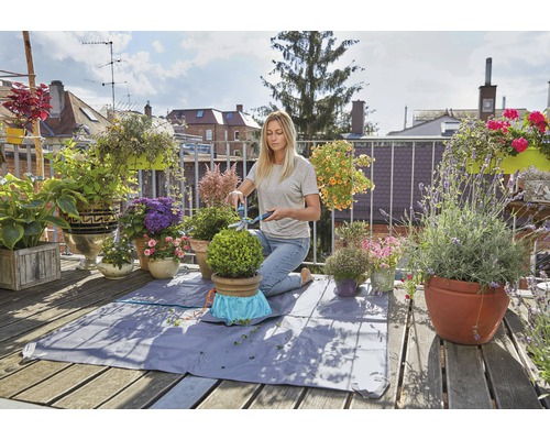Femme taillant un buis sur un balcon avec une natte de plantation