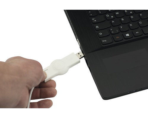 Un homme insère une clé USB blanche dans un ordinateur portable.