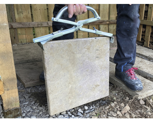 Mann hebt Gehwegplatte mit Steinzange