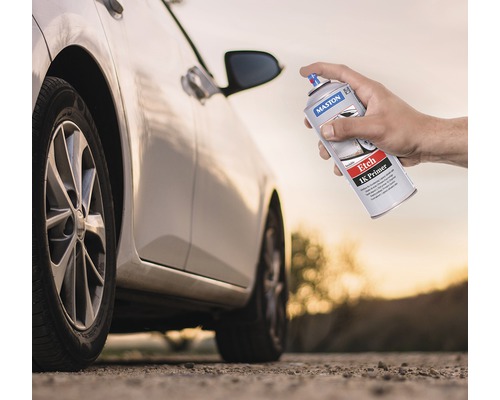 Eine Hand hält eine Spraydose Maston Etch 1K Primer vor einem Auto.
