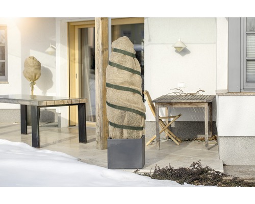 Terrasse avec sacs de protection des plantes et tables de jardin en hiver.